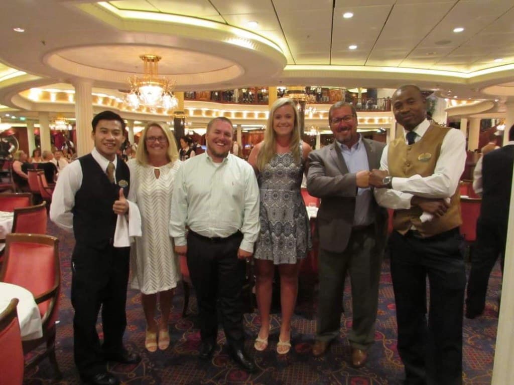 Brian Maylor with guests in a Royal Caribbean dining room — thirteen years of table service