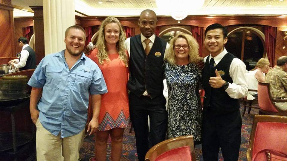 Brian Maylor with guests in a Royal Caribbean dining room — thirteen years of table service