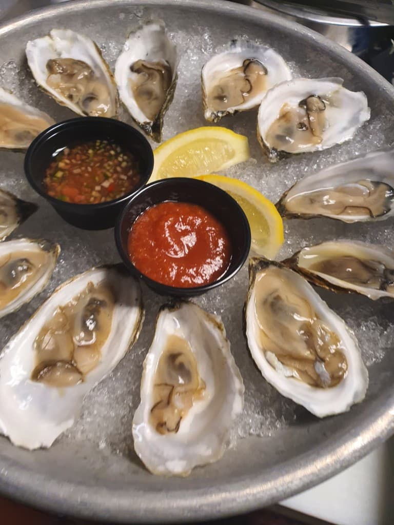 Freshly shucked oysters on ice with dipping sauces, sourced for a Bornfidis menu